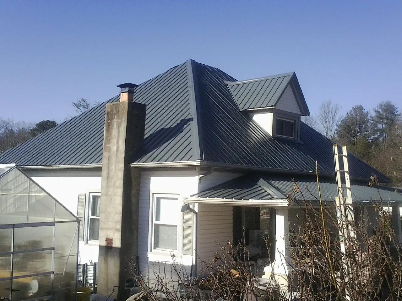 Dark blue standing seam metal roof on a white farmhouse with dormer — Slate & Tile Roof Repair by Roofing Brothers in Bernville