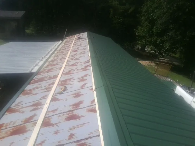 Old rusted panels beside newly installed green metal roofing — Wind Damage Roof Repair by Roofing Brothers in Bernville
