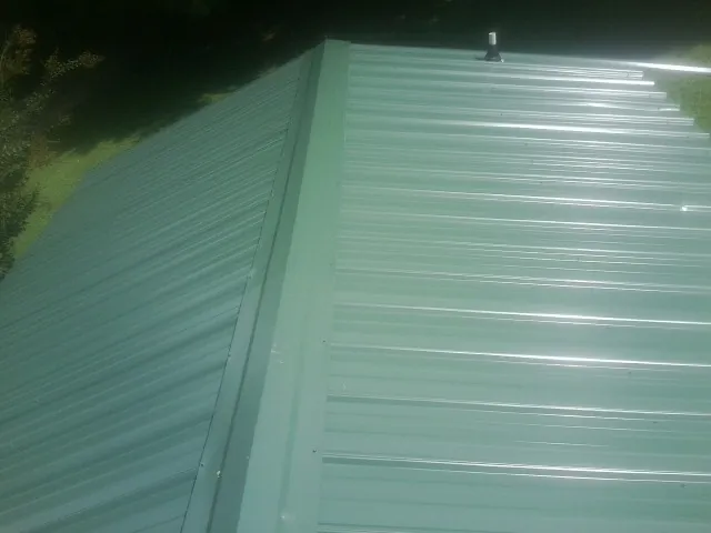 New green metal panels meeting at the ridge of a roof — Flat Roof Repair work by our crew in Bernville