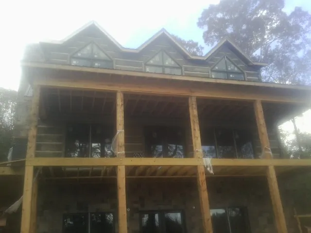 Dormers and porch framing on a large log home under construction — Roof Coating work by our crew in Bernville