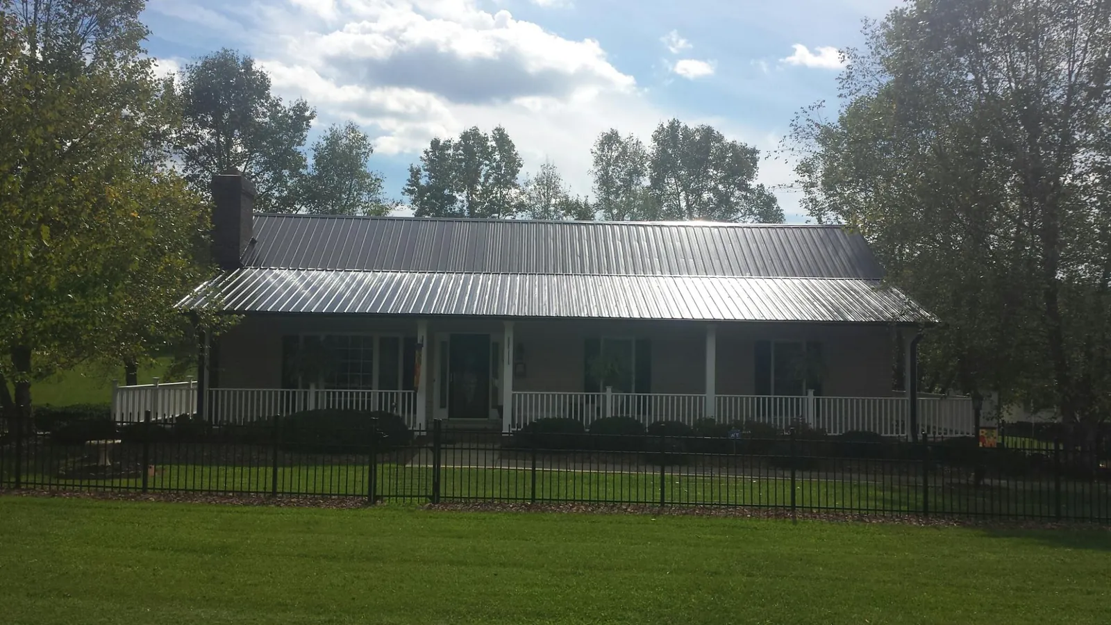 Gray metal roof on a brick ranch with a full width front porch — Gutter Guard Installation work by our crew in Bernville