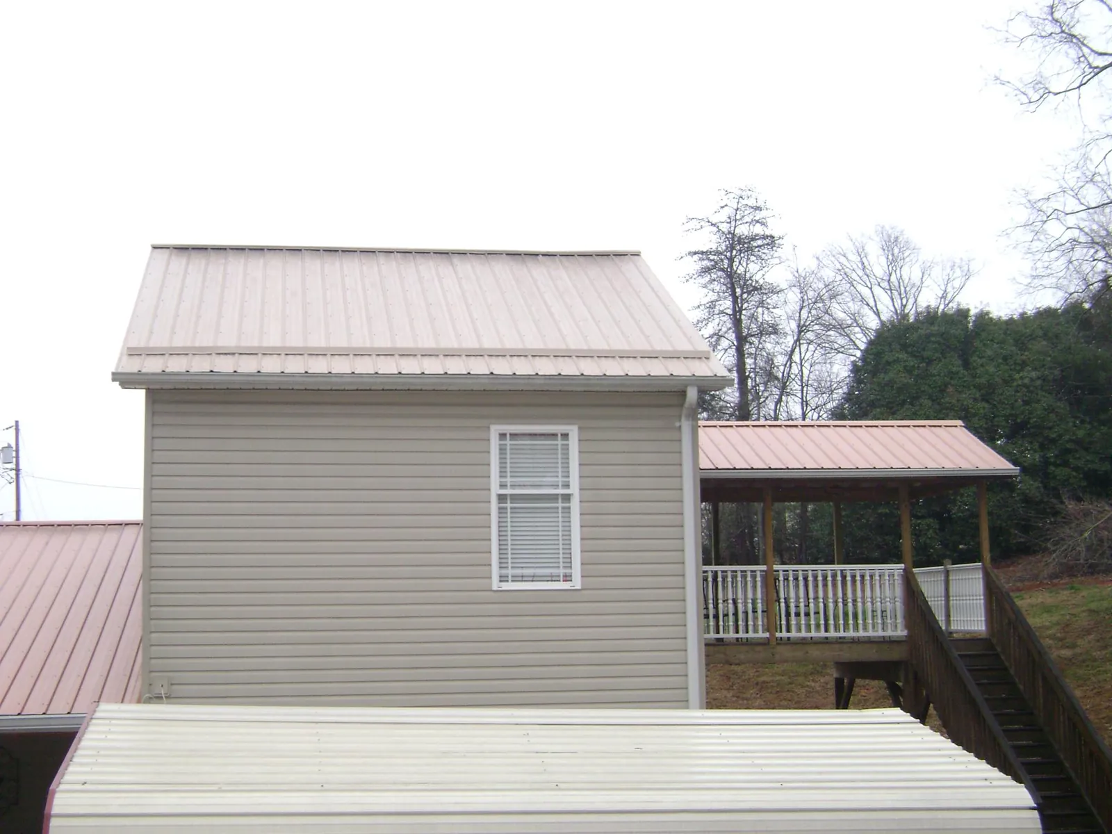 Tan metal roofs on a two story addition and attached porch, from a Roof Replacement job in Bernville