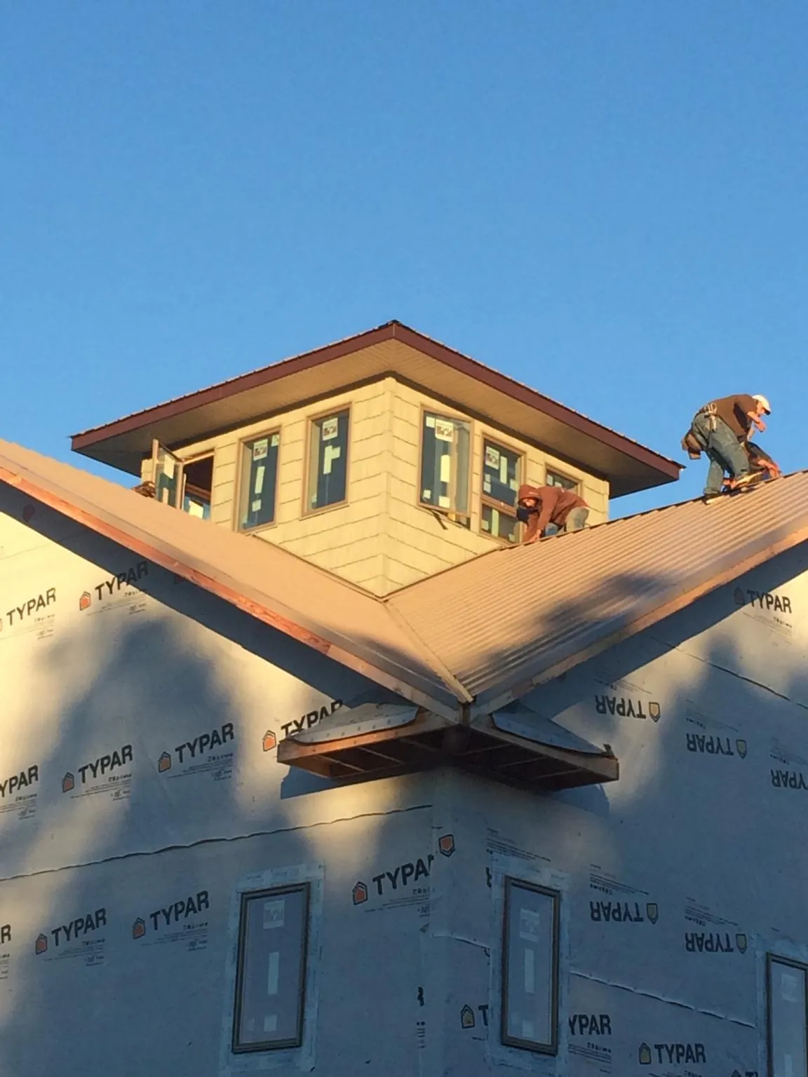 Roofers working around a rooftop cupola on a new metal roof at sunset — Roof Waterproofing in Bernville by Roofing Brothers